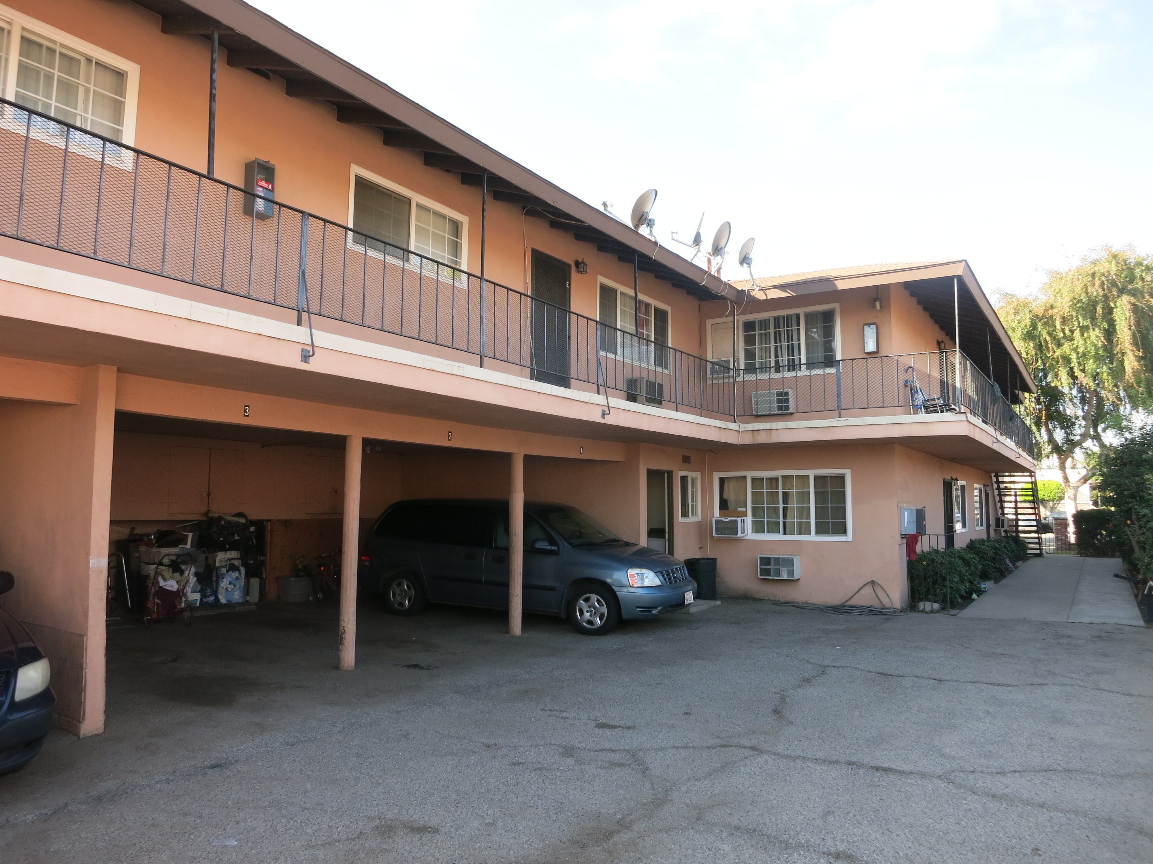 A carport with a black car and a blue car parked in it.